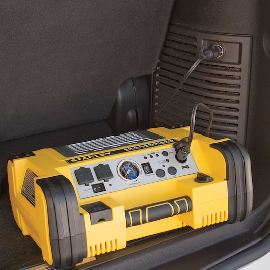 STANLEY PPRH5 portable power station and jump starter with yellow and black design in a car trunk, side view.