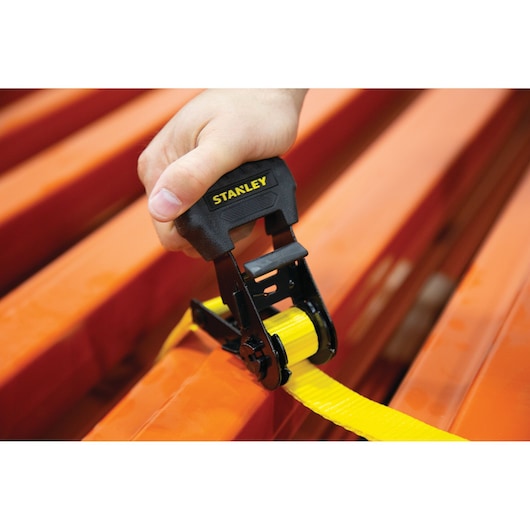 Photo of STANLEY S1006 ratchet tie down with yellow strap being tightened on orange beams.