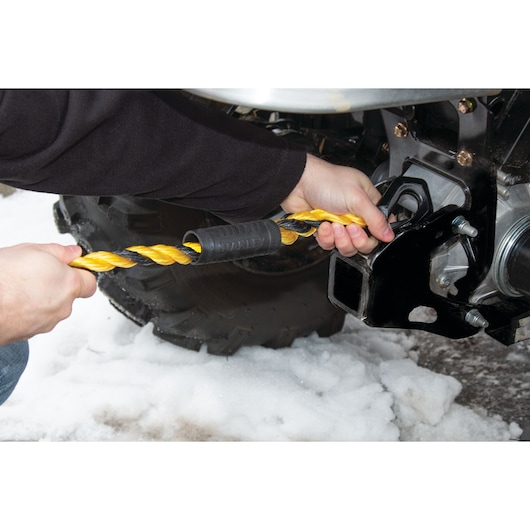 STANLEY S1052 twisted yellow tow rope being attached to a vehicle hitch in snowy conditions, close-up angle.