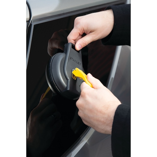 Photo of STANLEY S4004 suction cup tool being used on a car window, close-up of hands and tool.