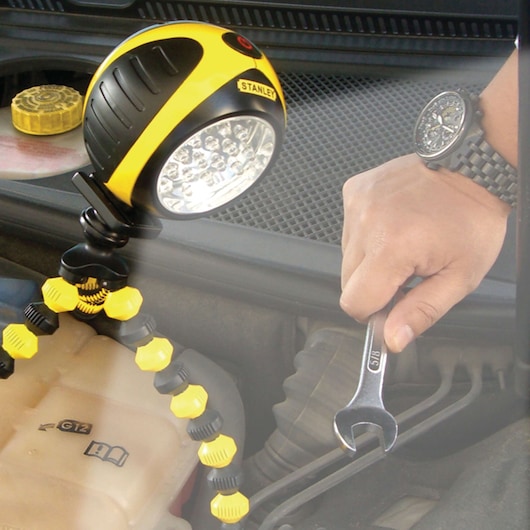 STANLEY SB01AL photography of a yellow and black LED work light on a flexible tripod, used during car engine repair.