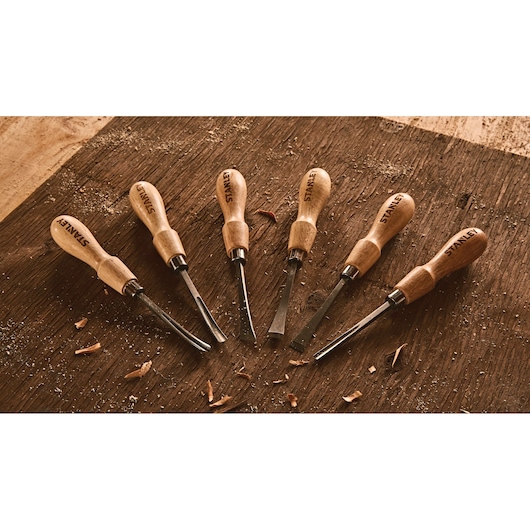 STANLEY STHT16863 wood chisel set with wooden handles arranged on a workbench, photography angle from above.