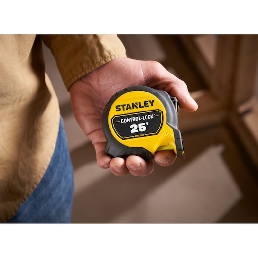 STANLEY STHT37244 25-foot Control-Lock tape measure held in a hand, yellow and black casing.