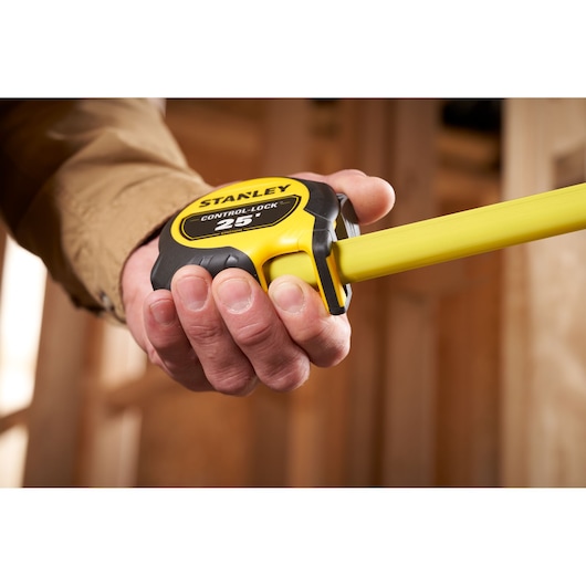 Stanley STHT37244 tape measure held in hand, yellow and black design, close-up side angle.