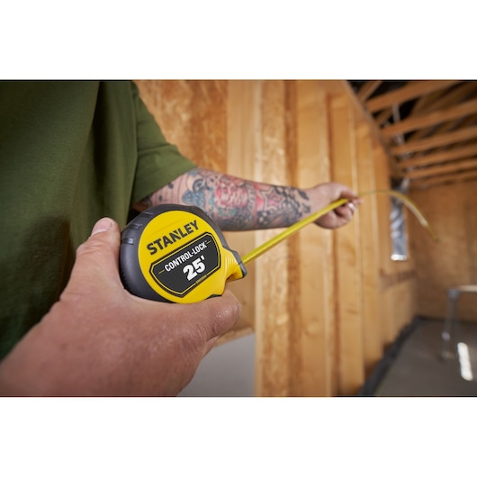 STANLEY STHT37244 tape measure with yellow casing and CONTROL LOCK 25' label in use at construction site.