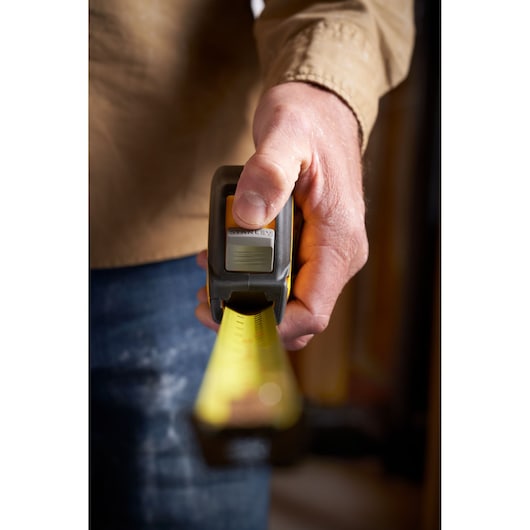 STANLEY STHT37244 tape measure held in hand, yellow blade extended for measurement.