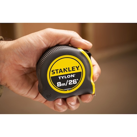 Stanley Tylon STHT39526 tape measure, 8m/26ft, black and yellow, held in hand.