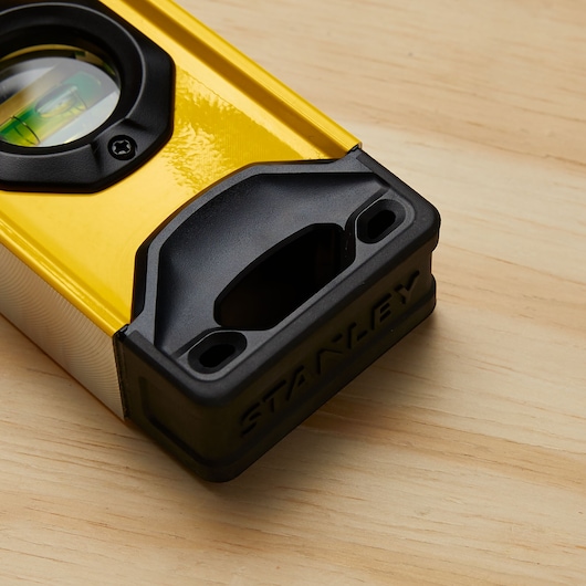 Stanley STHT42504 yellow level with black ends, photography on wood surface, angled close-up.