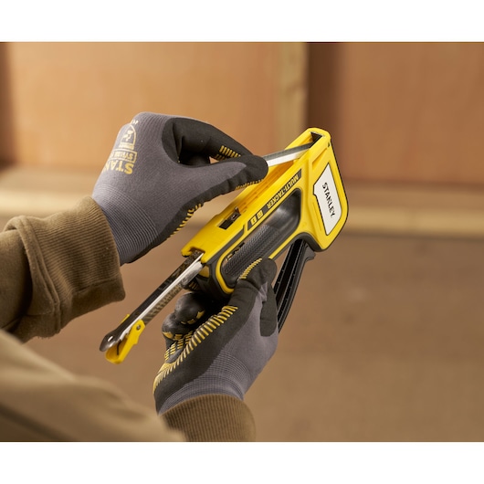 Stanley STHT70440 yellow multi-tacker stapler held in gloved hands, loading staples.