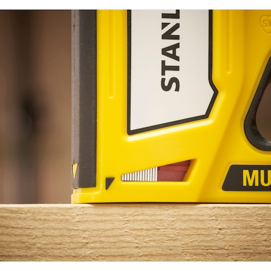Stanley STHT70440 yellow hand tool close-up resting on a wooden surface, partial side view.