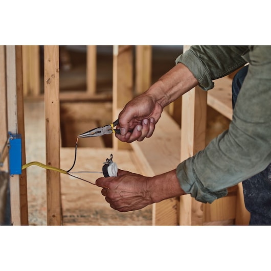 STANLEY STHT84402 long nose pliers used to grip wire during electrical installation in construction setting.