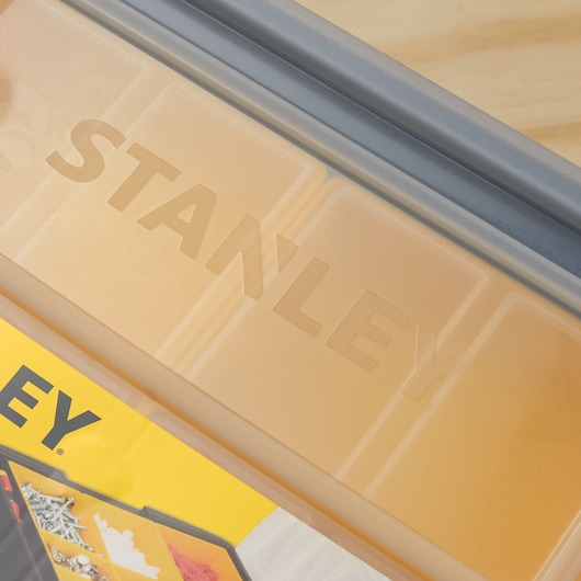 Stanley STST14028 organizer box lid with embossed brand logo, close-up angle, clear plastic compartments visible.