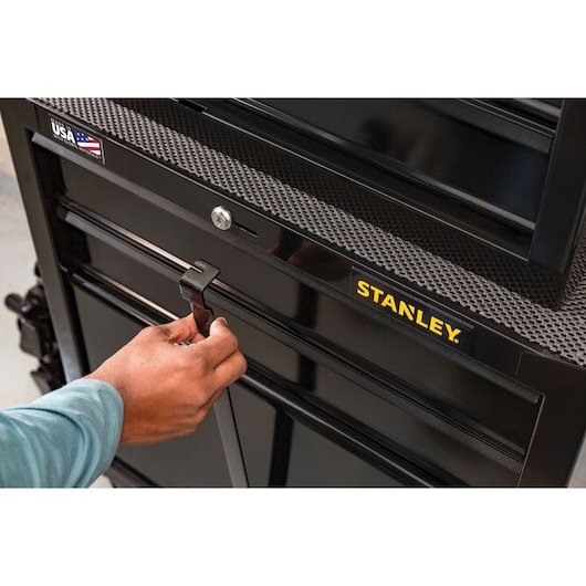 Photo of a hand opening a black STANLEY STST22656BK tool chest drawer, close-up angle showing logo.