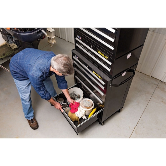 Stanley STST22753BK tool chest with open drawer, man organizing tools and accessories in a garage setting.