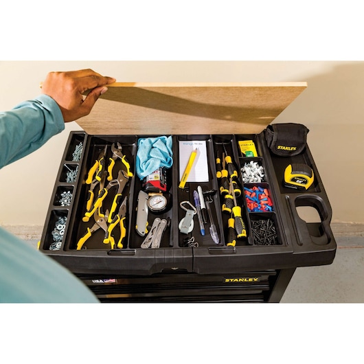 STANLEY STST23151BK tool organizer top view with hand opening lid, assorted yellow and black tools, screws, and tape measure.