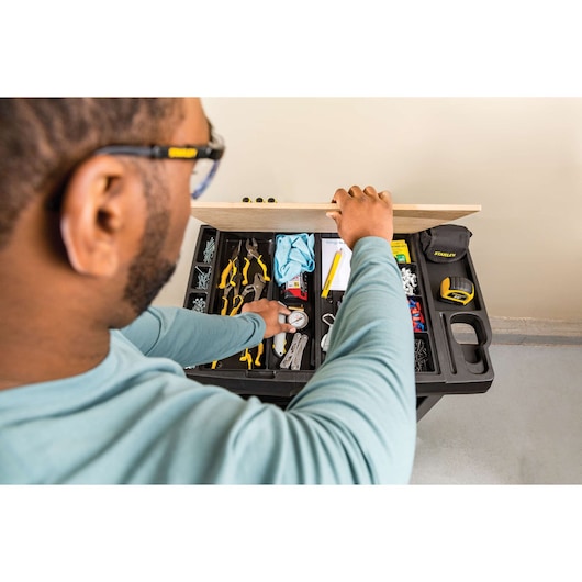 Photo of a person accessing a STANLEY STST23151BK tool cart with organized hand tools, tape measure, and hardware.