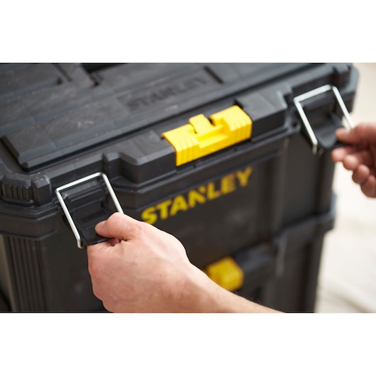 Stanley STST60500 photography of black tool chest with yellow latch, hands opening metal clasps