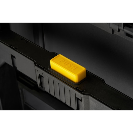 STANLEY STST60500 toolbox close-up showing yellow push button on black case, angled view.