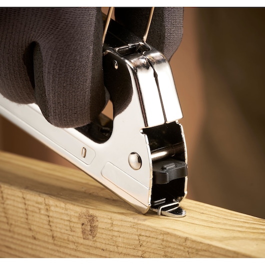 Stanley TR45 staple gun held by gloved hand stapling wood, close-up photo.