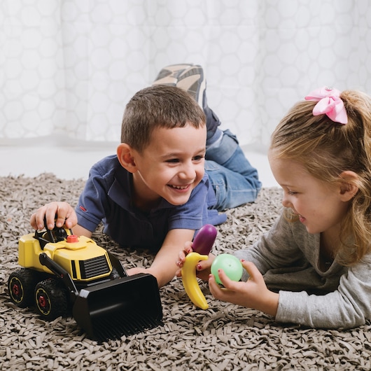STANLEY TT002-SY photography of two children playing on carpet with yellow toy truck and plastic fruit.