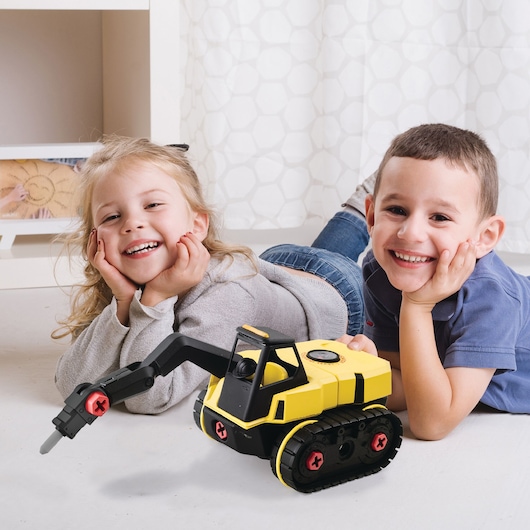 STANLEY TT010-SY toy excavator with yellow body, black tracks, and red accents on floor in front of two children.