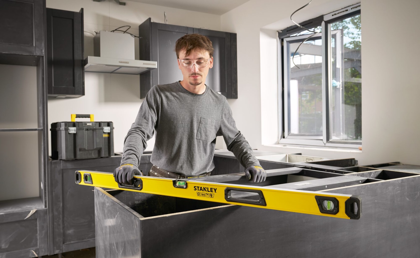 Stanley STHT41048 yellow box beam level used for cabinet installation in a modern kitchen setting.